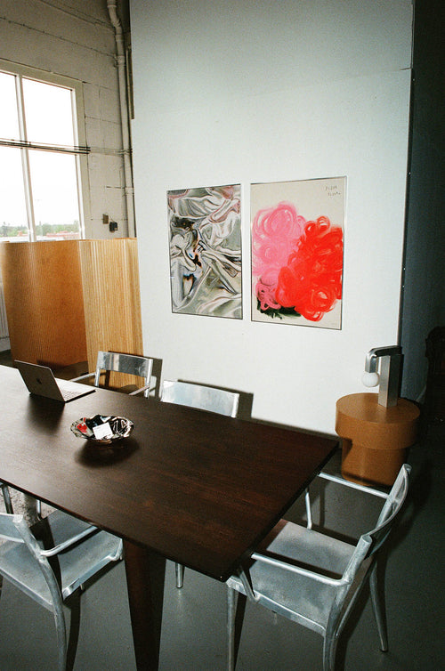 Modern dining area with a wooden table and chairs, featuring abstract art on the wall.