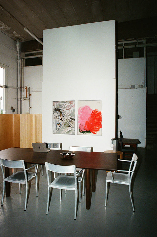 Modern dining area with a wooden table and chairs, featuring abstract art on the wall.