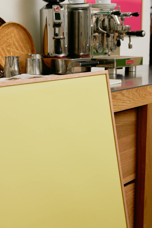 Coffee machine on a counter with a yellow cabinet in the foreground