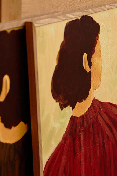 Partial view of a painting of a person with dark hair and a red garment, with another painting partially visible on the left.