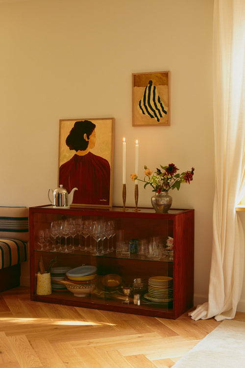 Room interior with a wooden sideboard, decorative items, and wall art.