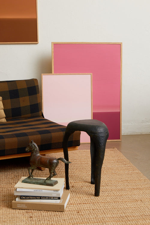 Art print with an abstract spray painting of a sky in light pink tones. Styled in a minimalist interior.