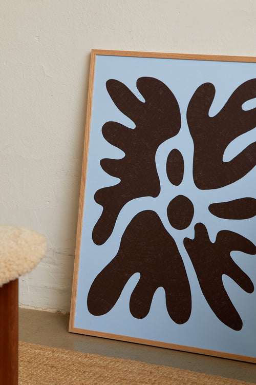 Art print featuring a minimalistic motif in chocolate brown and pastel blue, with shapes that explore the space between abstraction and recognition through soft, fluid forms. Styled in a minimalist interior.