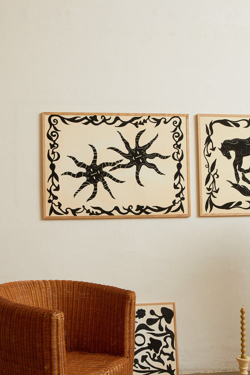 Art print with a minimalist illustration of black, organic, hand-drawn lines and suns against an off-white background. Styled in a minimalist interior.