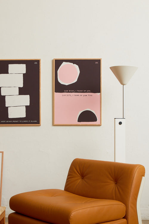 Art print with an abstract, minimalist painting in brown and pink that references a sunrise and a sunset. Styled in a minimalist interior.