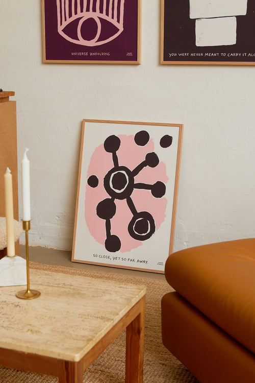 Art print with an abstract, minimalist painting in brown and pink referencing a distant universe, something that sometimes feels so close. Styled in a minimalist interior.