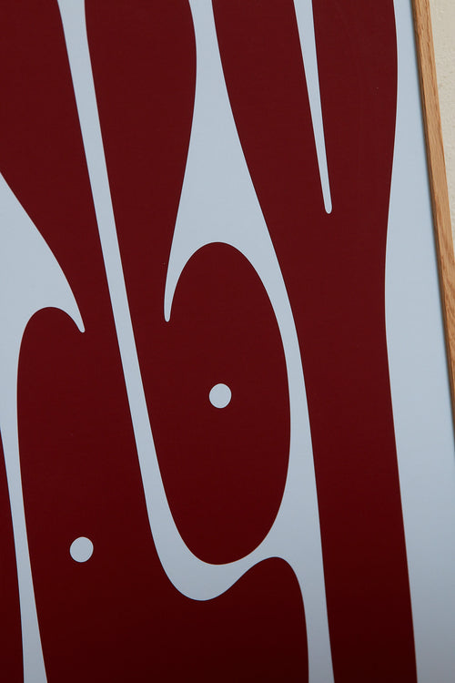 Art print featuring playful, bold typography of the word “Baby” in burgundy against a light blue background. Styled in a minimalist interior.