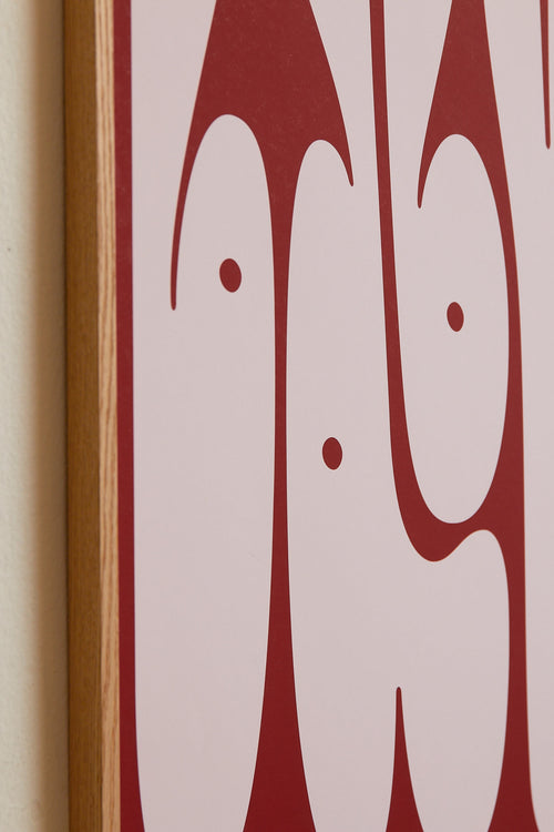 Art print featuring playful, bold typography of the word “Baby” in pink against a red background. Styled in a minimalist interior.