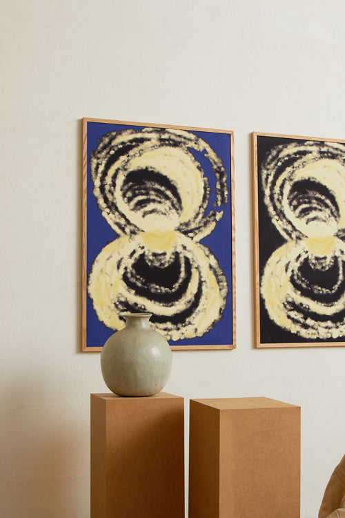 Art print with an abstract illustration of circular forms in light tones against a cobalt blue background, with a soft and organic expression. Styled in a minimalist interior.