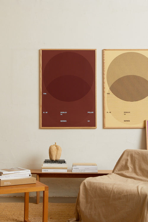 Art print with a graphic illustration of circular forms built from overlapping lines, complemented by small text elements, in brown, blue, and red RAL colors. Styled in a minimalist interior.