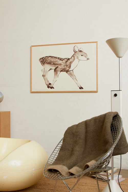 Art print with a stylized illustration of a fawn in gray-brown tones against a, with a soft and graphic expression. Styled in a minimalist interior.