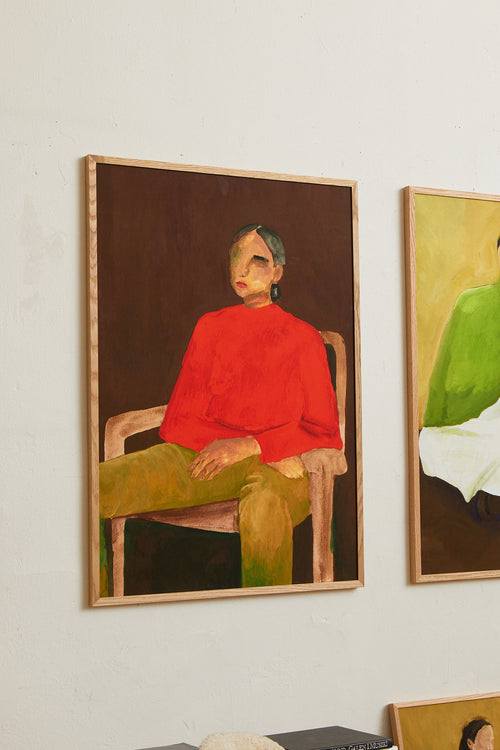 Art print featuring a painting of a person in a red sweater on a wooden chair against a deep brown background. Styled in a minimalist interior.