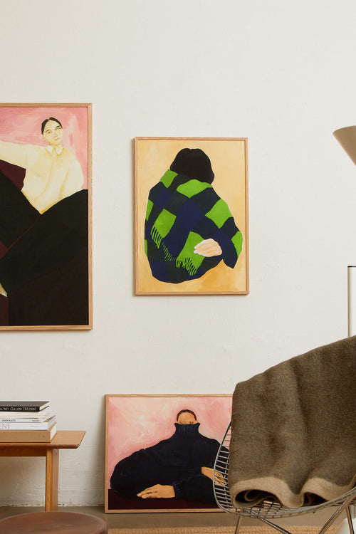 Art print featuring a painting of a person’s back, with a bright green shawl wrapped around the body against a beige background. Styled in a minimalist interior.