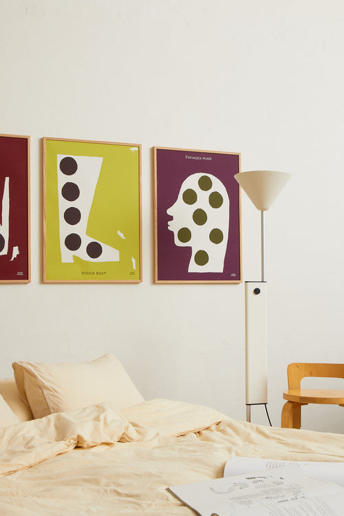 Framed burgundy print styled above a bed in a warm, softly decorated bedroom