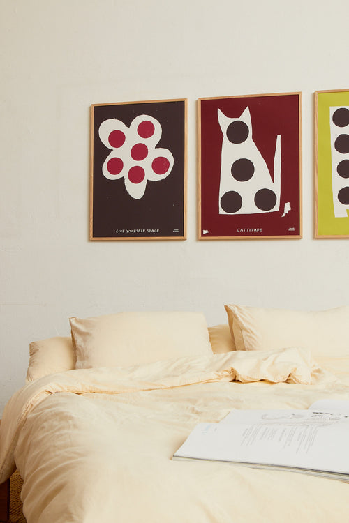 Framed red cat print styled above a bed in a warm bedroom interior