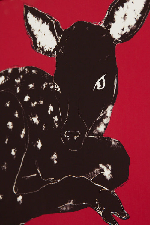 Art print with a stylized illustration of a lying deer in a dark tone against a bright red background, with a minimalist and graphic expression. Styled in a minimalist interior.
