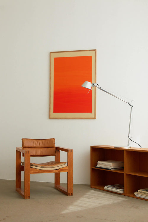 Wooden chair and bookshelf with a red abstract painting on a white wall.