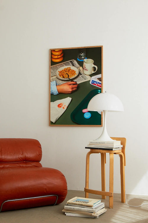 Living room with a red sofa, wooden stool, and framed artwork on the wall.