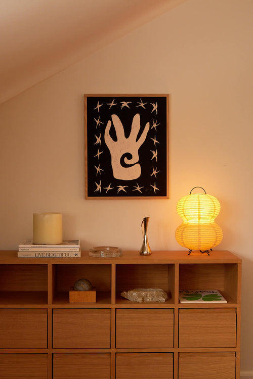 Wooden shelf with decorative items and a framed artwork on a wall.