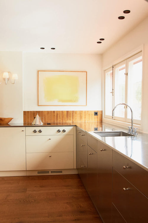 Modern kitchen with white cabinets, a yellow backsplash, and a sink.