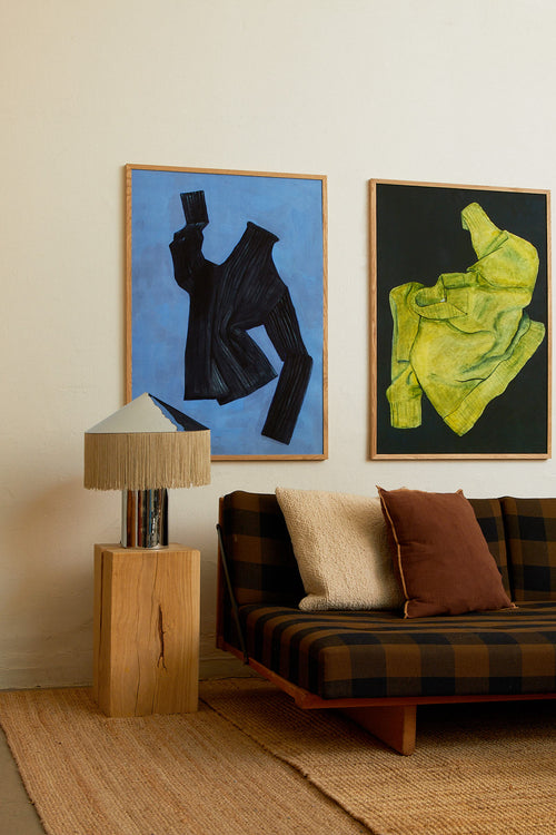 Living room with a sofa, lamp, and two framed artworks on the wall.