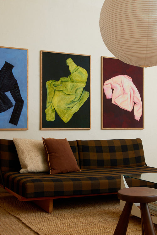 Living room with a plaid sofa, colorful abstract paintings on the wall, and a pendant light.