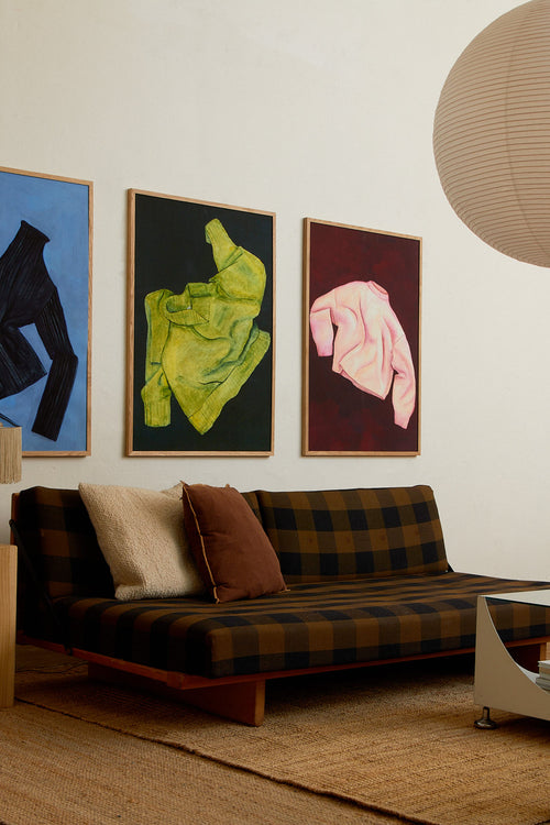 Living room with a plaid sofa, colorful abstract paintings on the wall, and a pendant light.