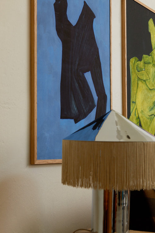 Framed abstract art on a wall with a lamp in the foreground