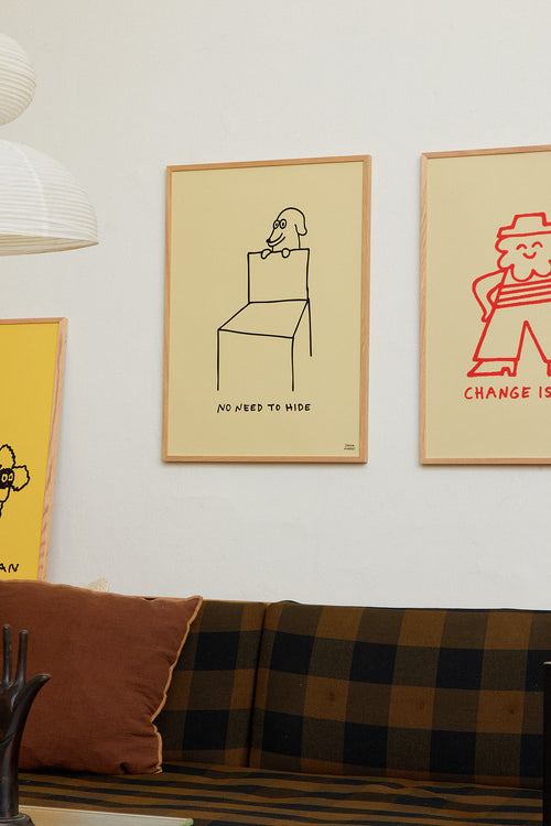 Framed artworks on a wall above a sofa with a plaid pattern