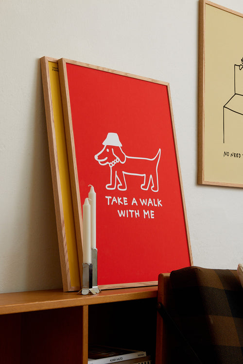 Red framed poster with a dog illustration and text on a shelf.