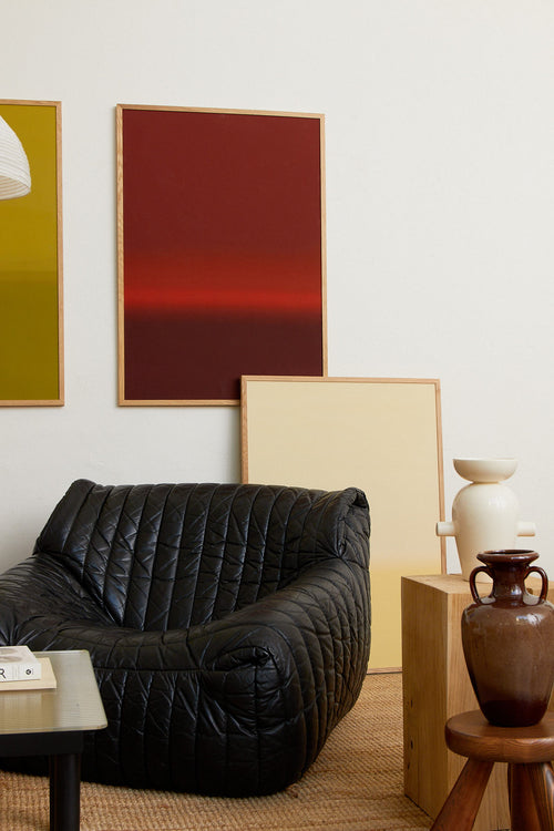 Modern living room with a black sofa, abstract art, and decorative items.