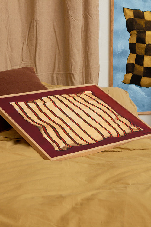 Striped pillow on a bed with a colorful painting in the background