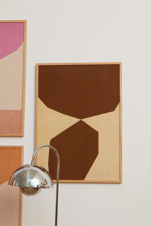 Abstract art pieces on a wall with a floor lamp.