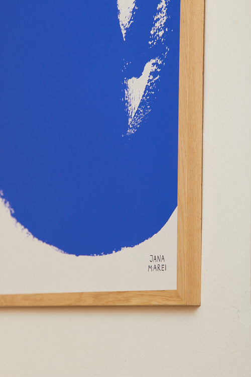 Framed abstract art print with blue and white design on a beige wall