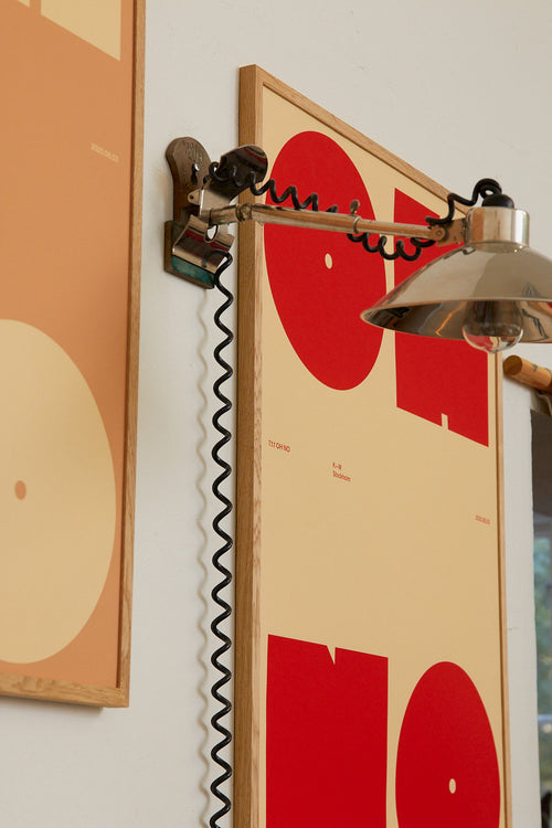 Wall-mounted lamp with a red and beige abstract art piece on a white wall.