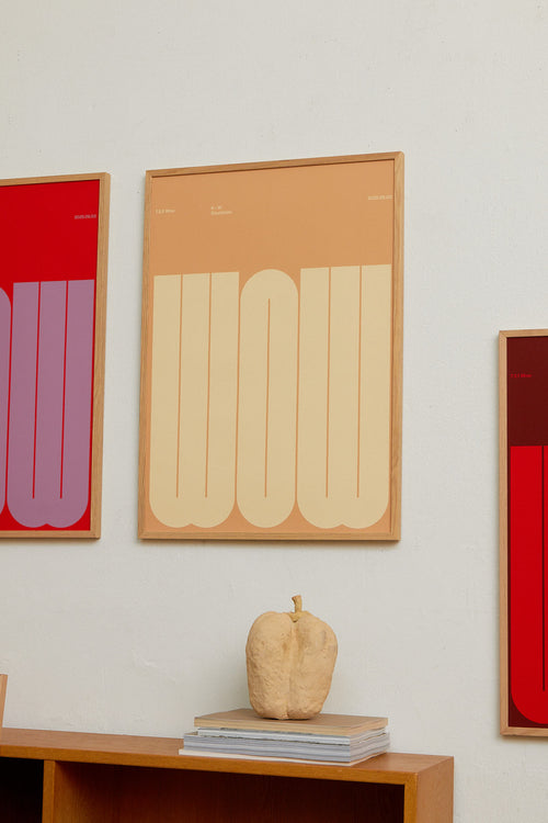 Three framed artworks with abstract designs on a wall above a wooden shelf.