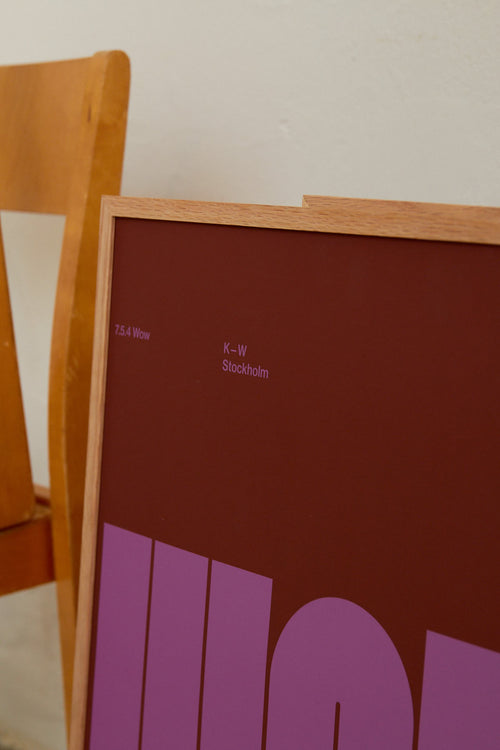 Framed poster with text on a wooden chair against a light background