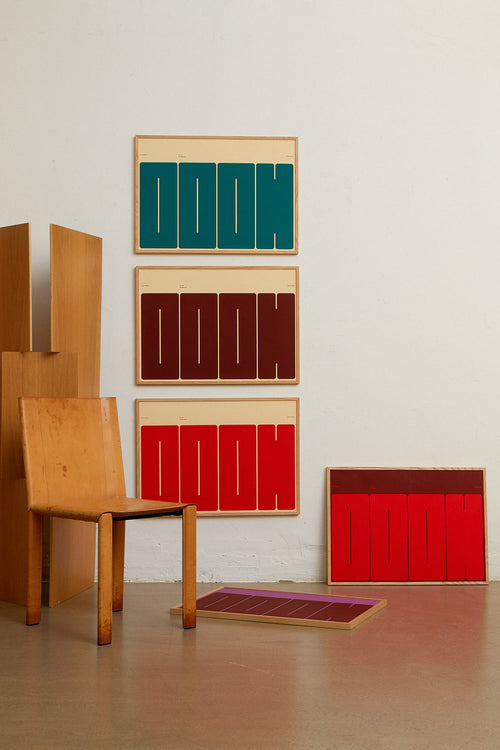 Colorful abstract wall art pieces on a white wall with a wooden chair.