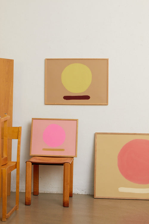 Three abstract art pieces on a wall with wooden furniture.