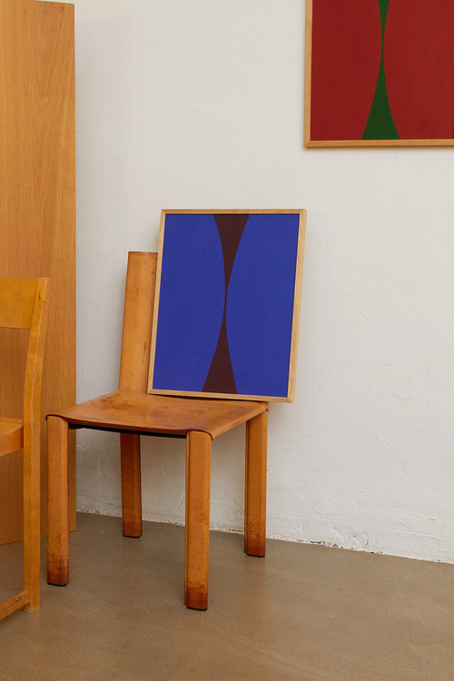 Wooden chair with a blue abstract painting on its backrest against a white wall.
