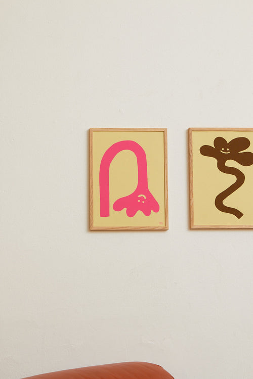 Two framed abstract artworks on a wall, one pink and one brown.