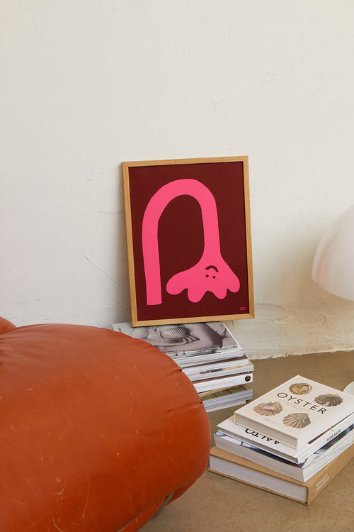 Framed pink abstract art on a stack of books with a textured surface