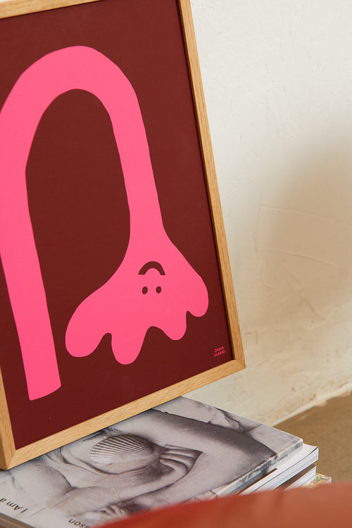 Framed pink abstract art on a surface with a blurred background