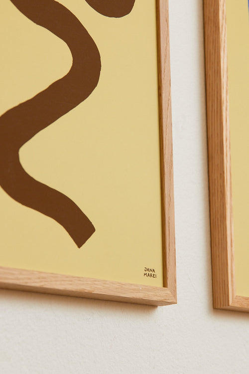 Framed abstract art piece with a wavy brown line on a beige background