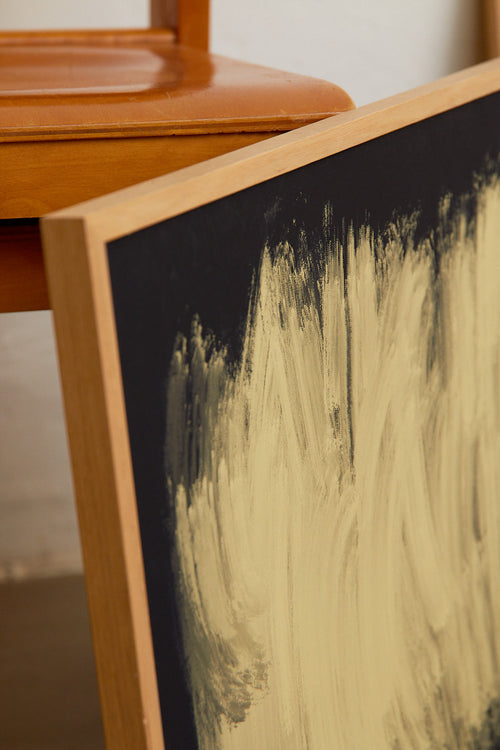Close-up of a wooden frame with black and gold brush strokes on a blurred background