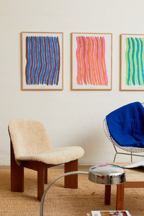 Blue striped print styled above a chair in a modern interior