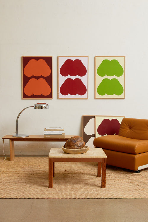 Art print featuring playful, bold typography of the text “MM”, the sound of enjoyment, in red against a pink background. Styled in a minimalist interior.