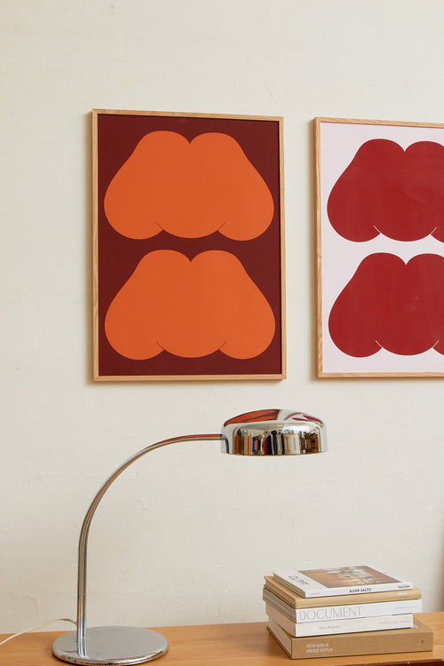 Art print featuring playful, bold typography of the text “MM”, the sound of enjoyment, in rust orange against a dark brown background. Styled in a minimalist interior.