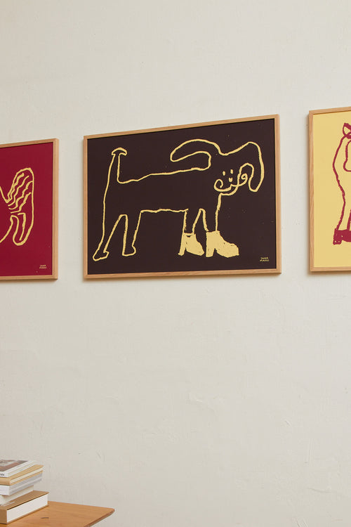 Interior scene with the dark brown dog print displayed alongside other colorful artworks on the wall