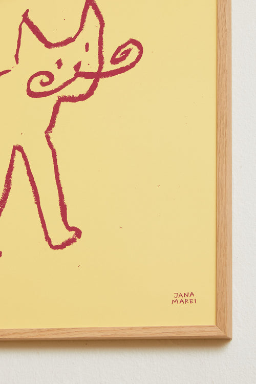 Side view of the framed yellow cat print displayed against a light wall